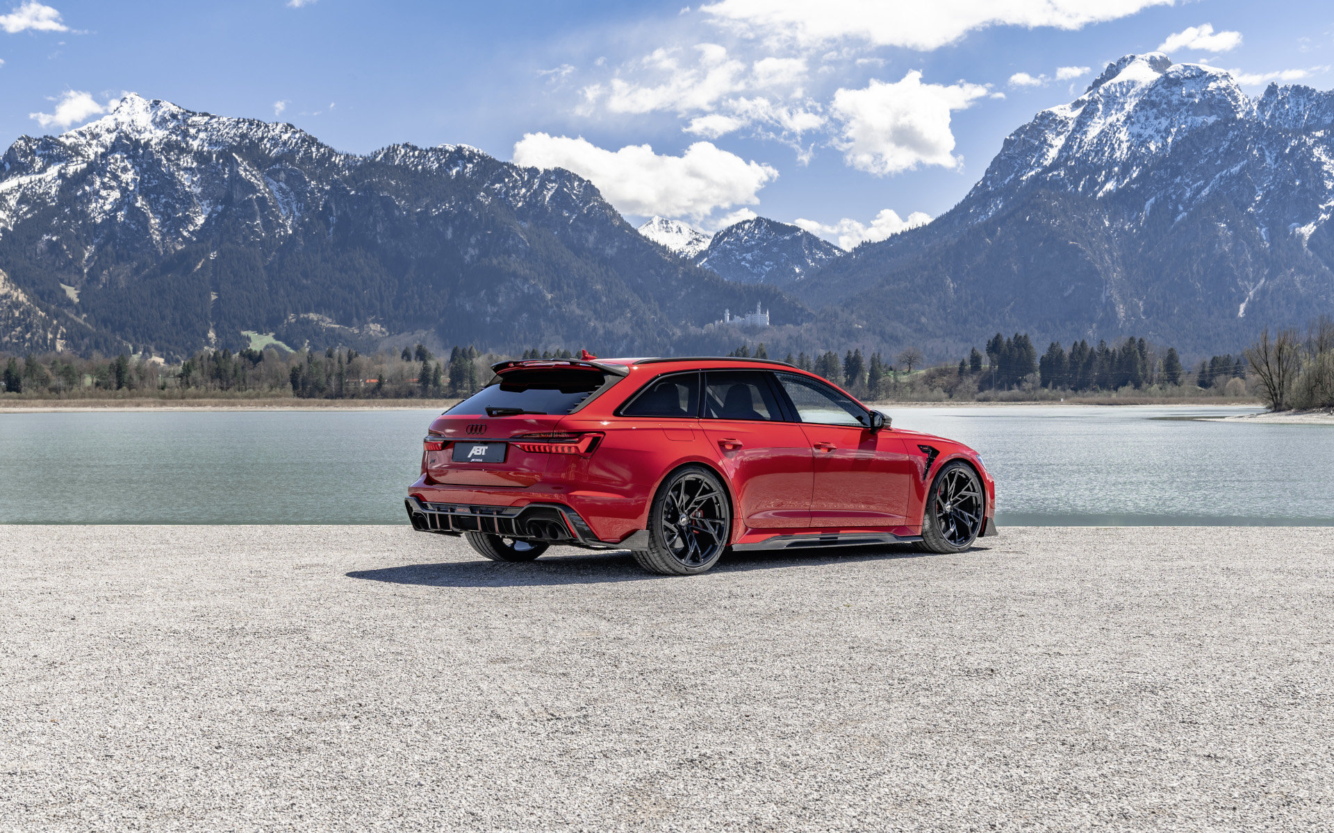 roter RS6-LE aus der seitlichen Heckperspektive vor See mit Bergpanorama